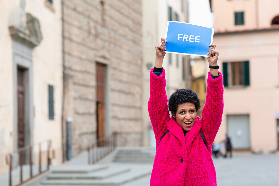Italy, Tuscany, Pistoia, Woman in pink coat holding up sign