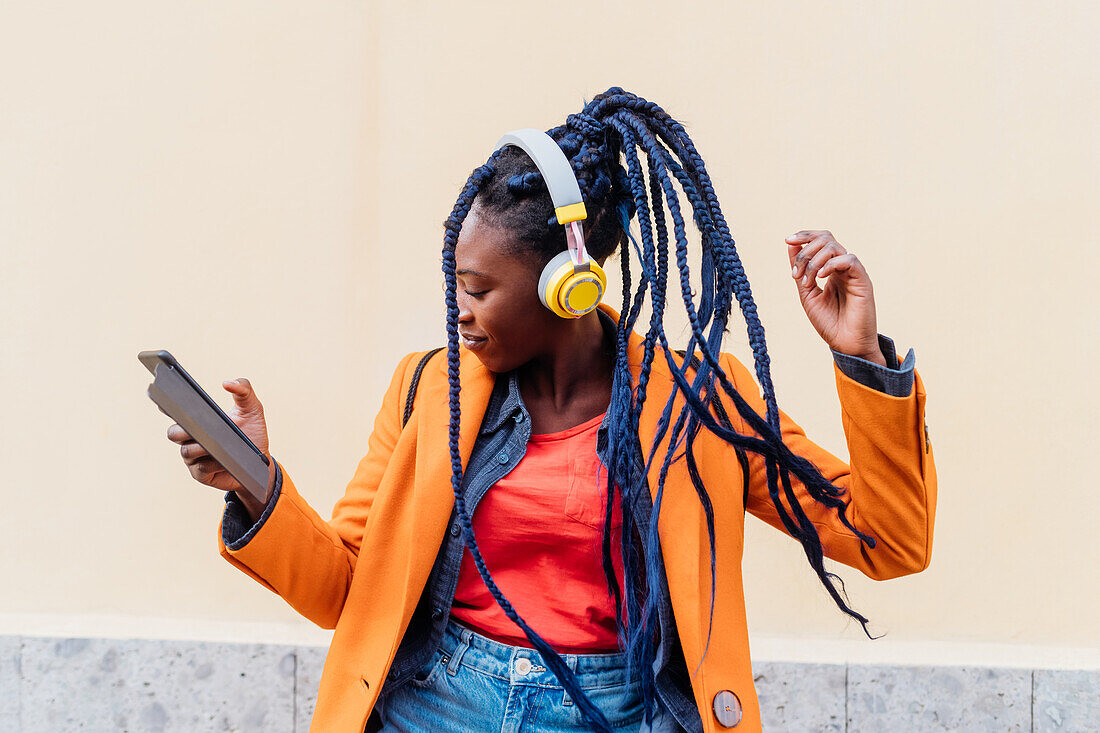 Italy, Milan, Woman with headphones and smart phone dancing outdoors