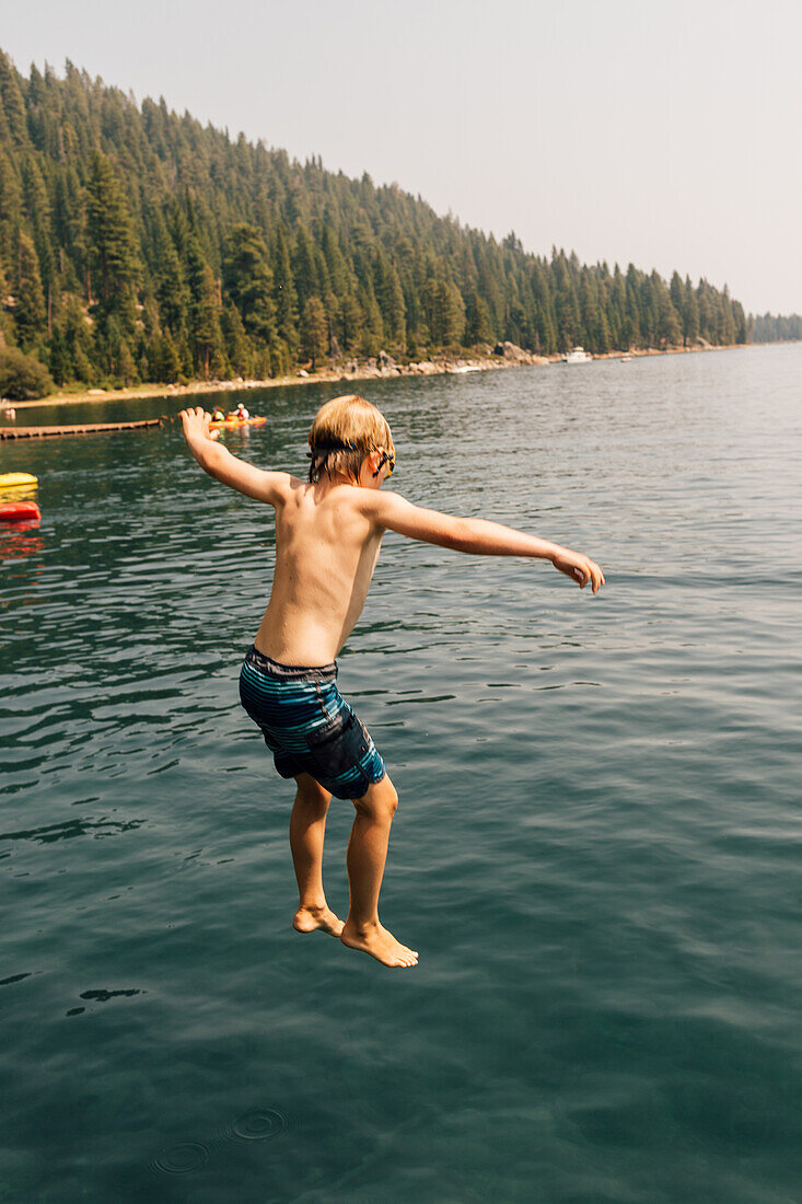 Boy (8-9) jumping into lake