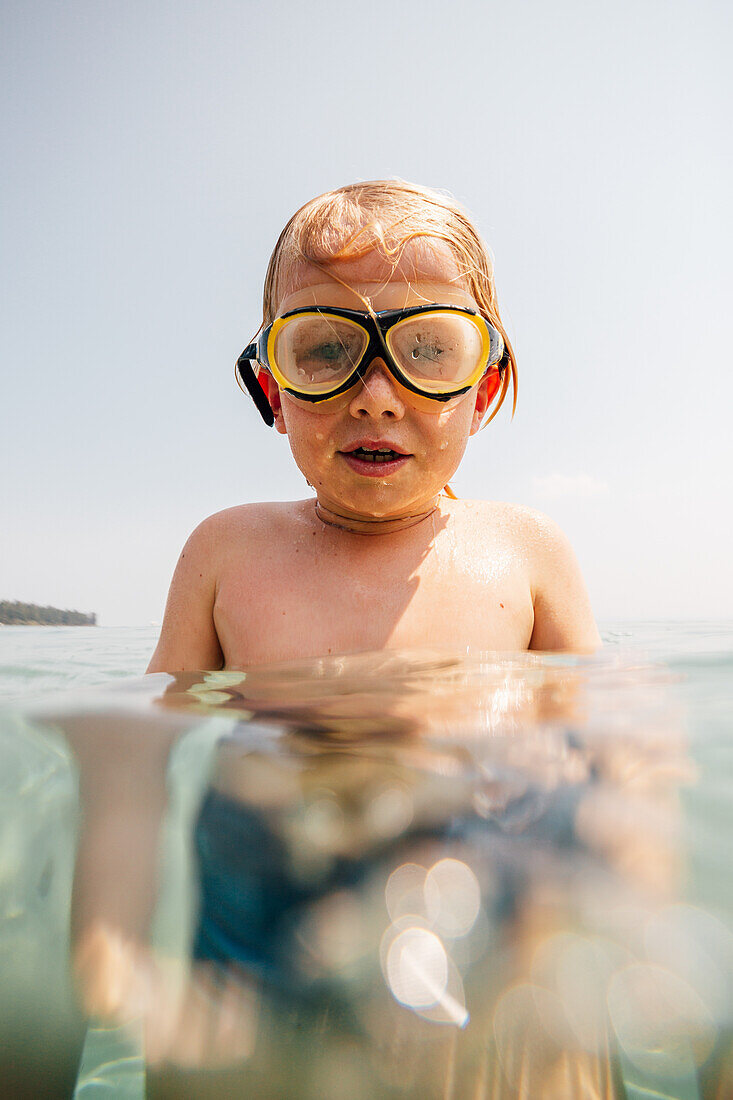 Portrait of boy (8-9) in swimming goggles in lake