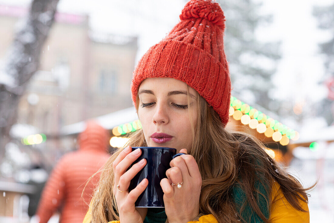 Young woman blowing on hot drink
