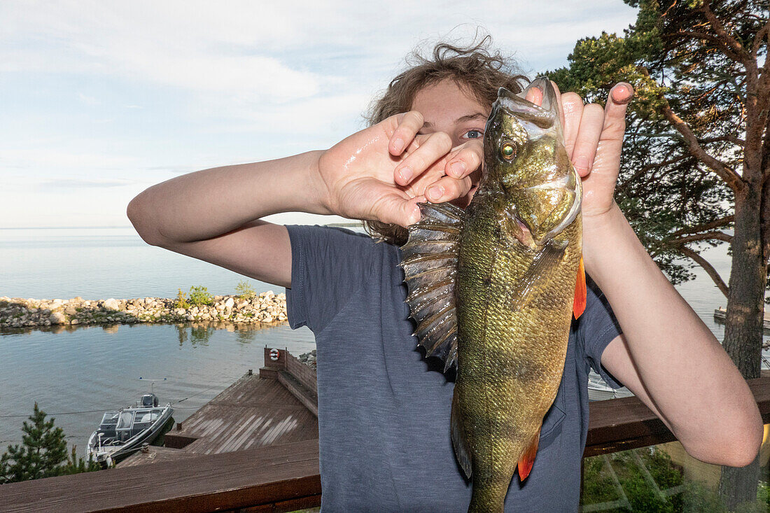 Boy (14-15) holding freshly caught fish