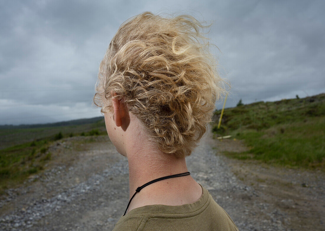 UK, Schottland, Nahaufnahme eines jungen blonden Mannes in einer Landschaft an einem windigen Tag