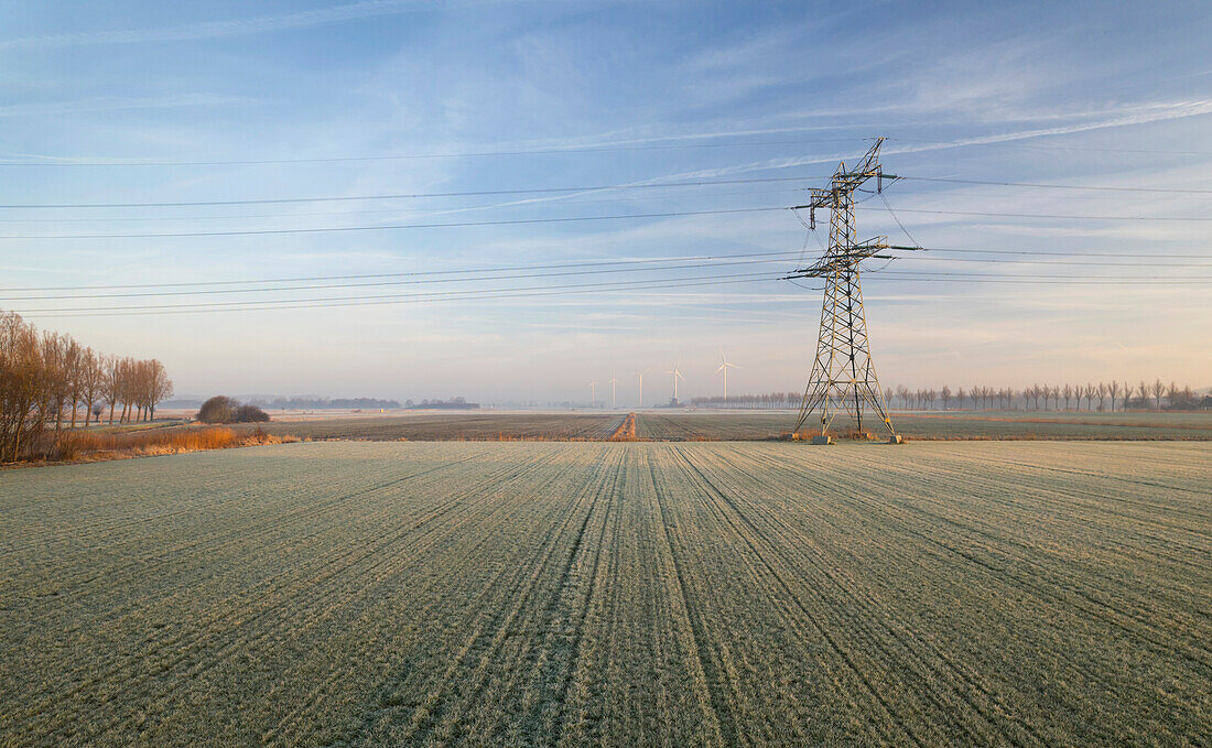 Niederlande, Noord-Brabant, Stromleitung und gefrorenes landwirtschaftliches Feld