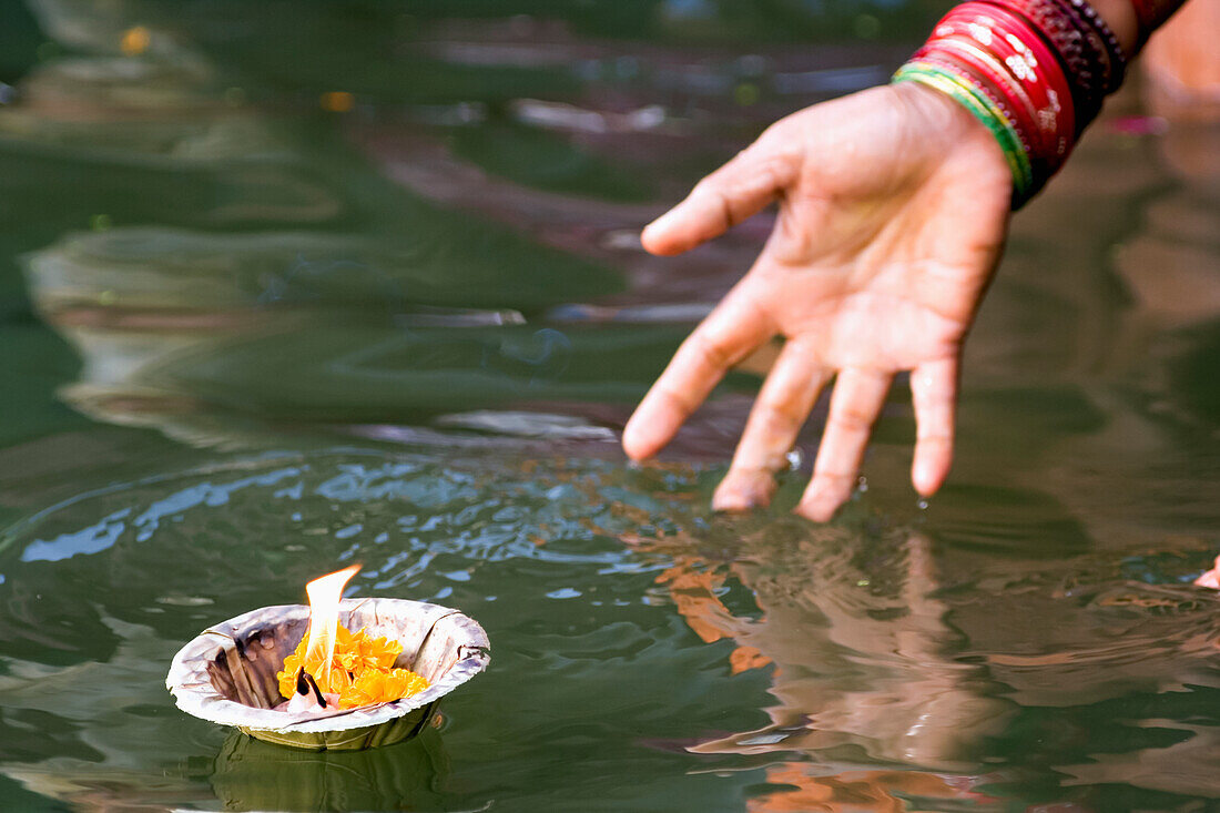 Hindu Woman Immersed In The Holy Ganges Water, Casting Off A Container With A Flame As A Religious Offering; Uttar Pradesh State, India