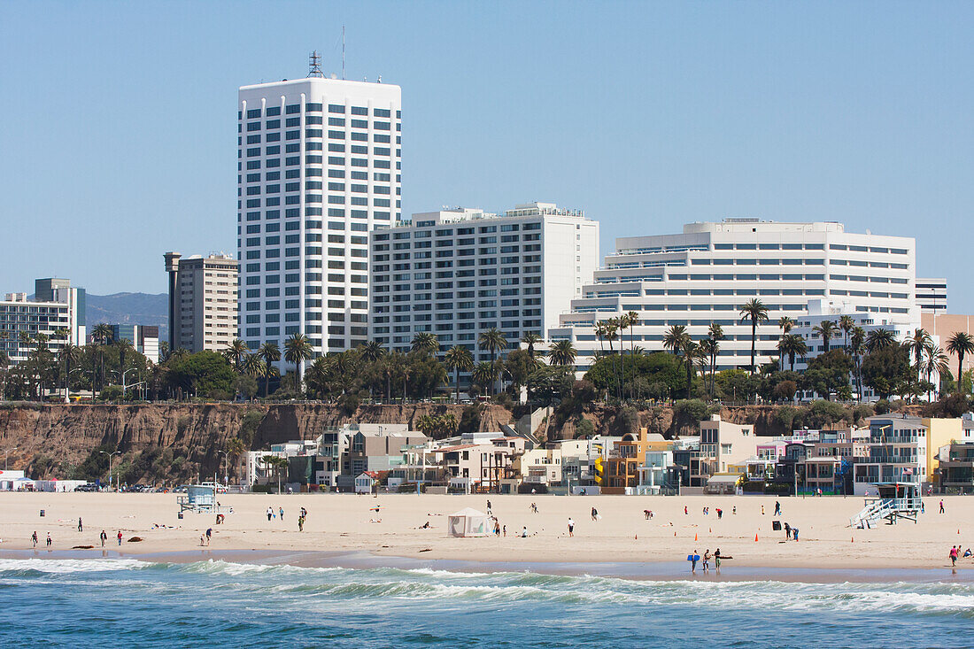 Strand am Wasser mit Häusern, Gebäuden und Palmen im Hintergrund; Kalifornien, Vereinigte Staaten von Amerika