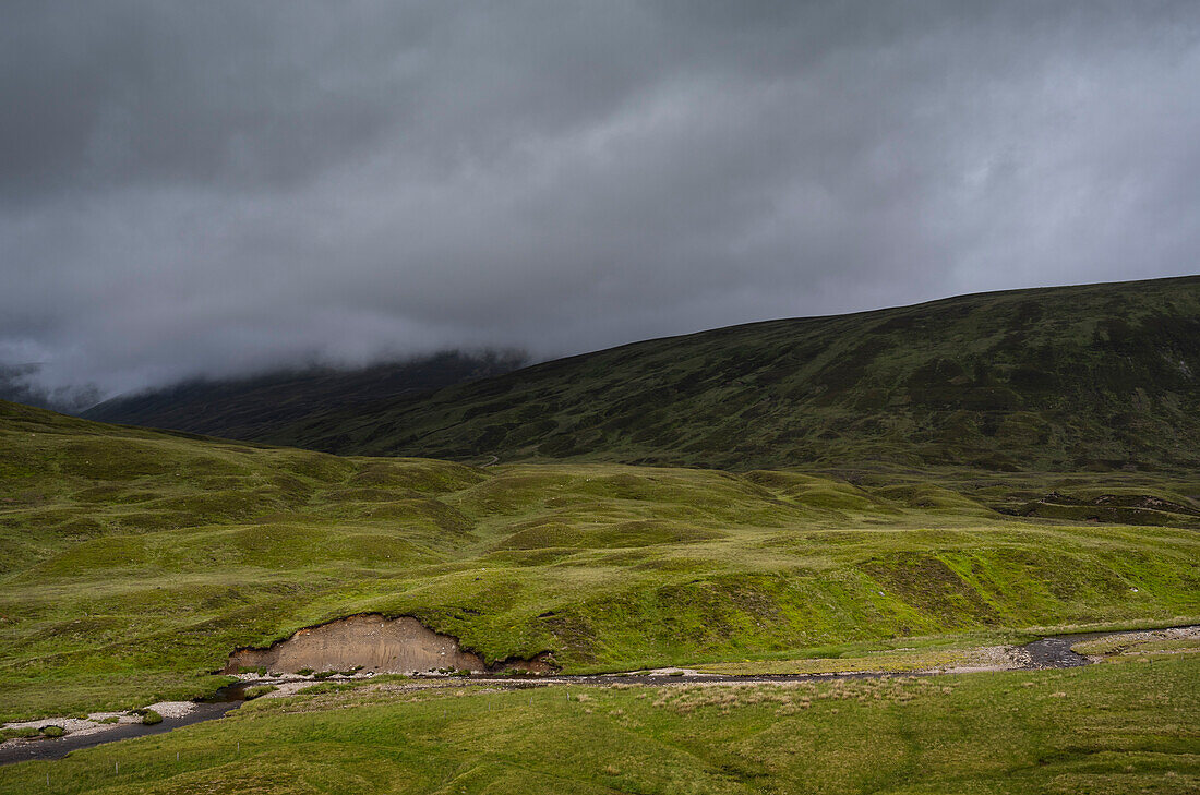 UK, Schottland, Gewitterwolken über grünem Hügel