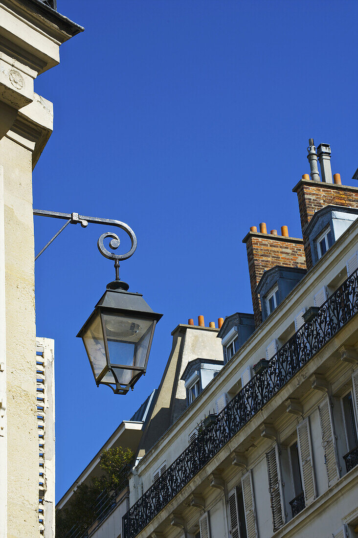 Fassade und Schornsteine eines Wohngebäudes mit einem Licht im Marais-Viertel; Paris, Frankreich.