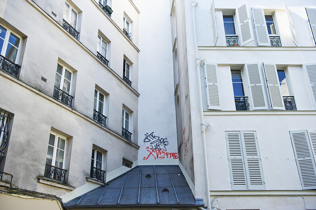 Ein weißes Wohnhaus mit Graffiti an der Außenwand; Paris, Frankreich.