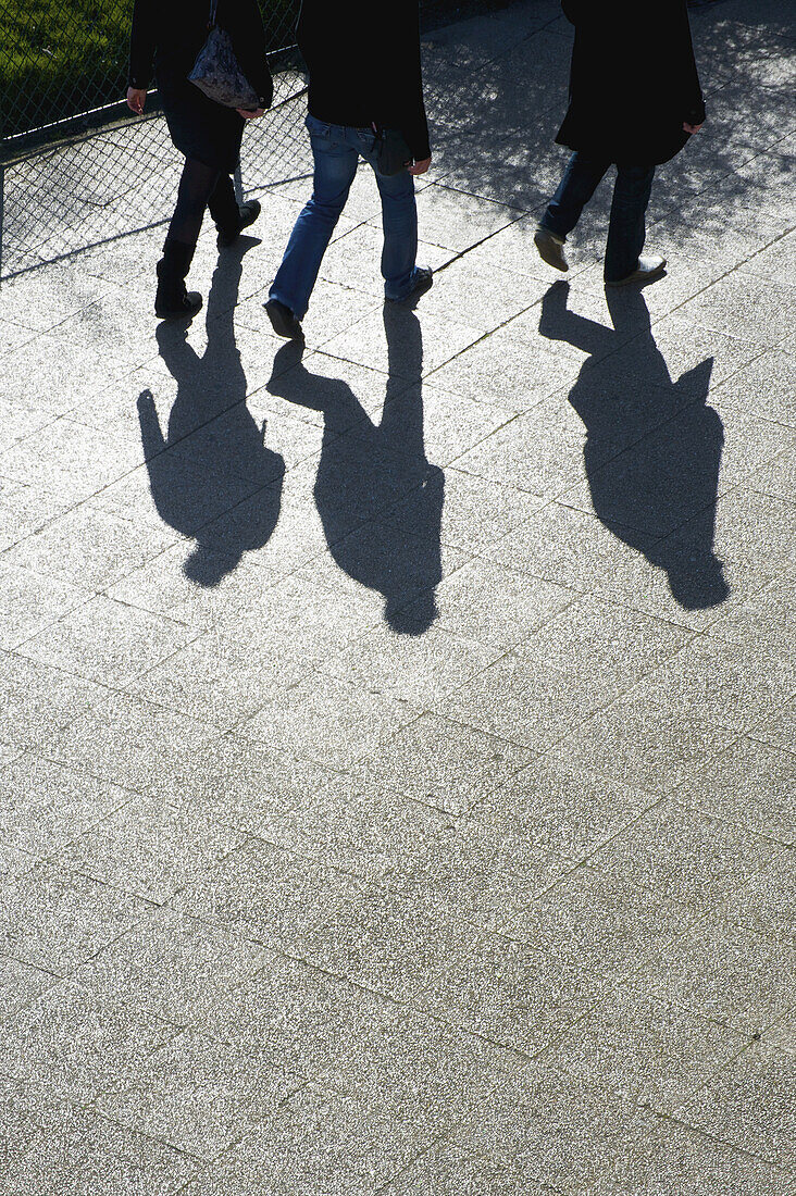 Fußgänger und ihre Schatten auf einem Gehweg; Paris, Frankreich.