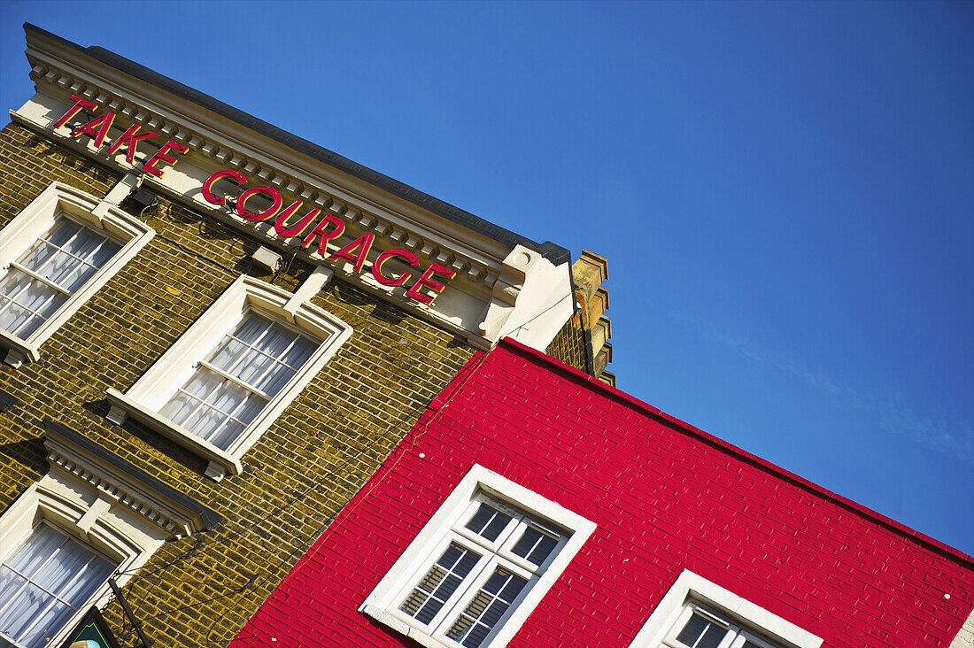 A Brick Building With A Sign That Says Take Courage, Camden; London, England