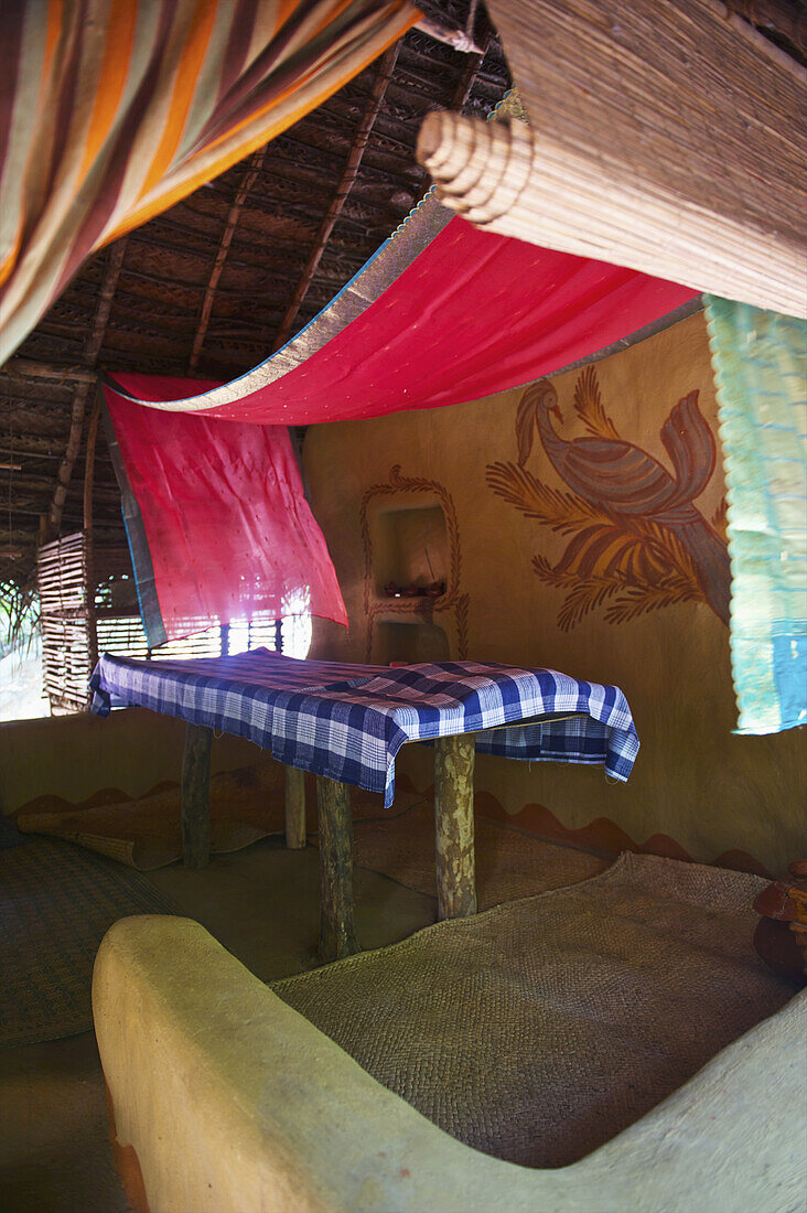 Ein Massagetisch, bedeckt mit rotem Dekorationsstoff, der von der Decke herabhängt; Ulpotha, Embogama, Sri Lanka