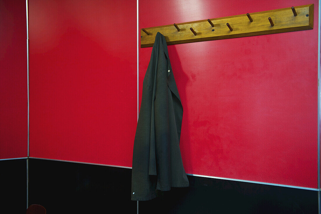 A Jacket Hangs On A Hook Mounted On A Bright Red Wall; London, England