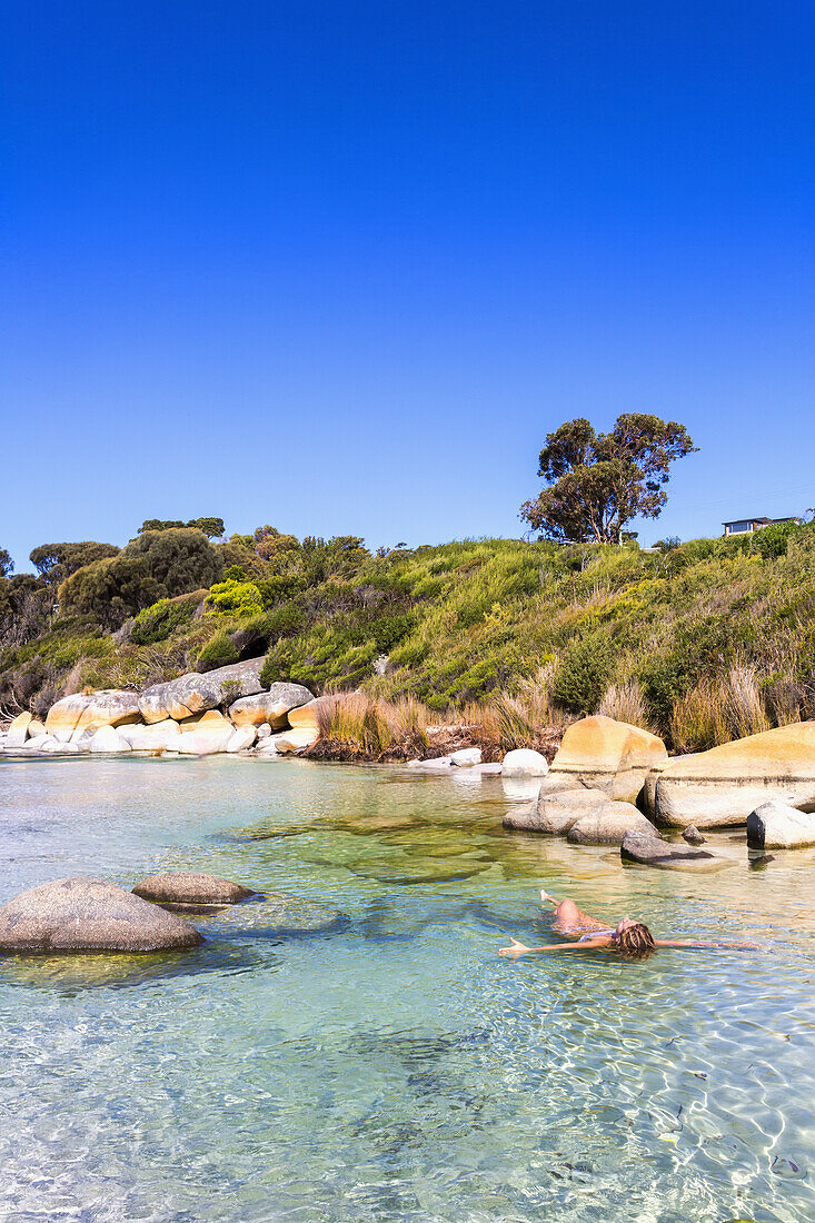 A Young Woman Swims At Bay Of Fires Beach; Tasmania, Australia