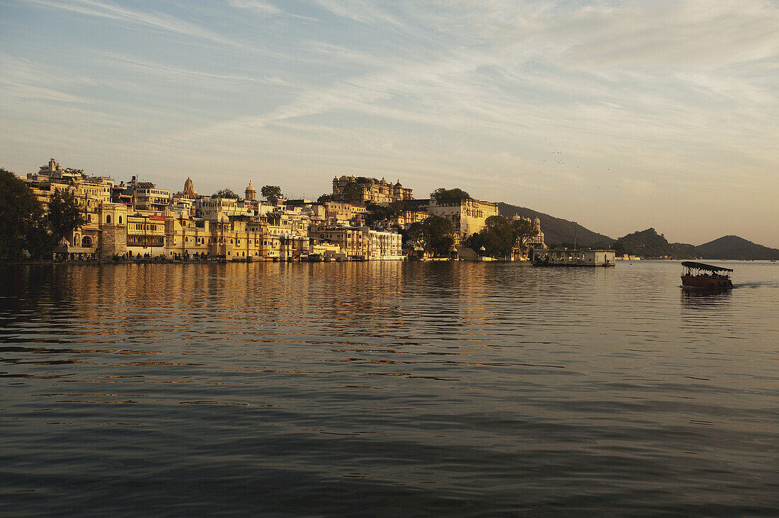 Buildings Glowing In The Sunlight Of The Setting Sun Along The River; Udaipur, India