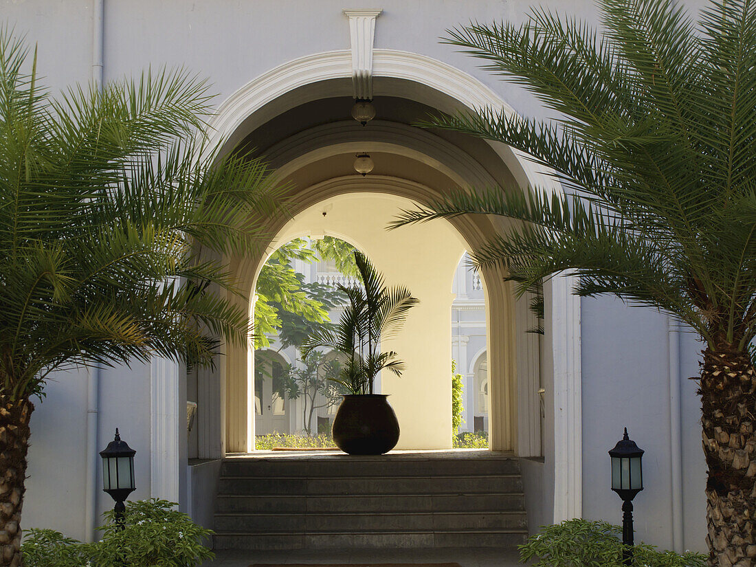 Steps Leading Up Into An Arched Entryway With Lamp Posts And Palm Trees