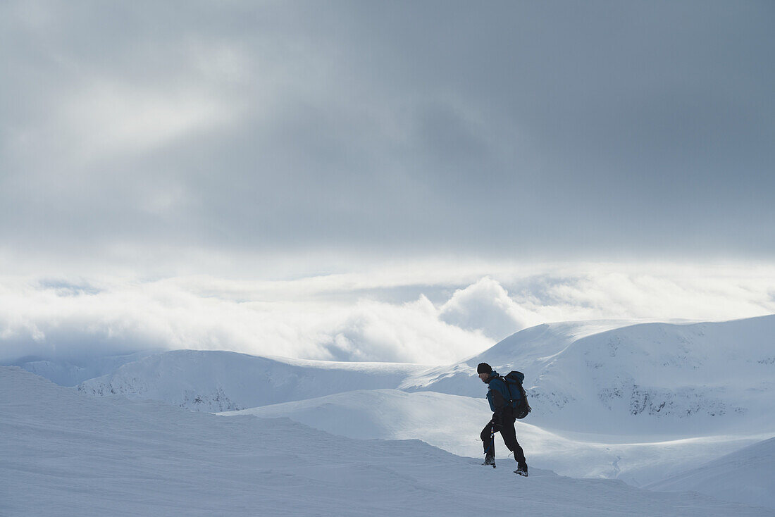Wanderer auf verschneitem Winterspaziergang beim Aufstieg zum Geal Charn, in der Nähe von Laggan; Schottland.