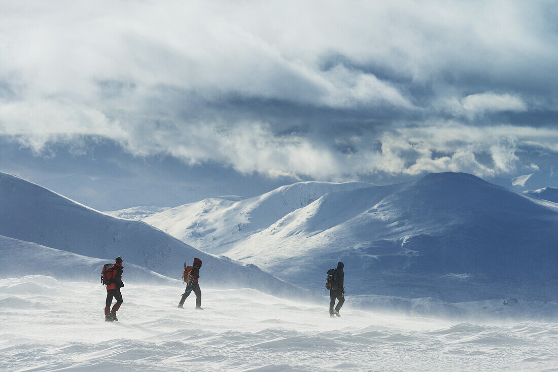 Drei Wanderer auf verschneitem Winterspaziergang beim Aufstieg zum Geal Charn, in der Nähe von Laggan; Schottland.