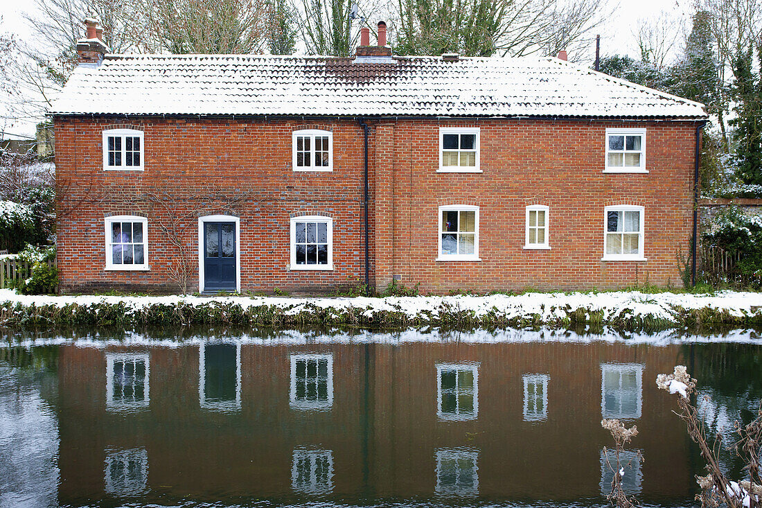 Haus am Rande eines Kanals, das sich im ruhigen Wasser spiegelt; Winchester, Hampshire, England