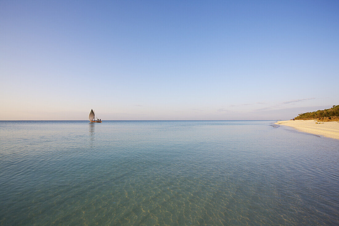 Ein Segelboot in der Ferne auf dem ruhigen Wasser des Indischen Ozeans; Vamizi-Insel, Mosambik