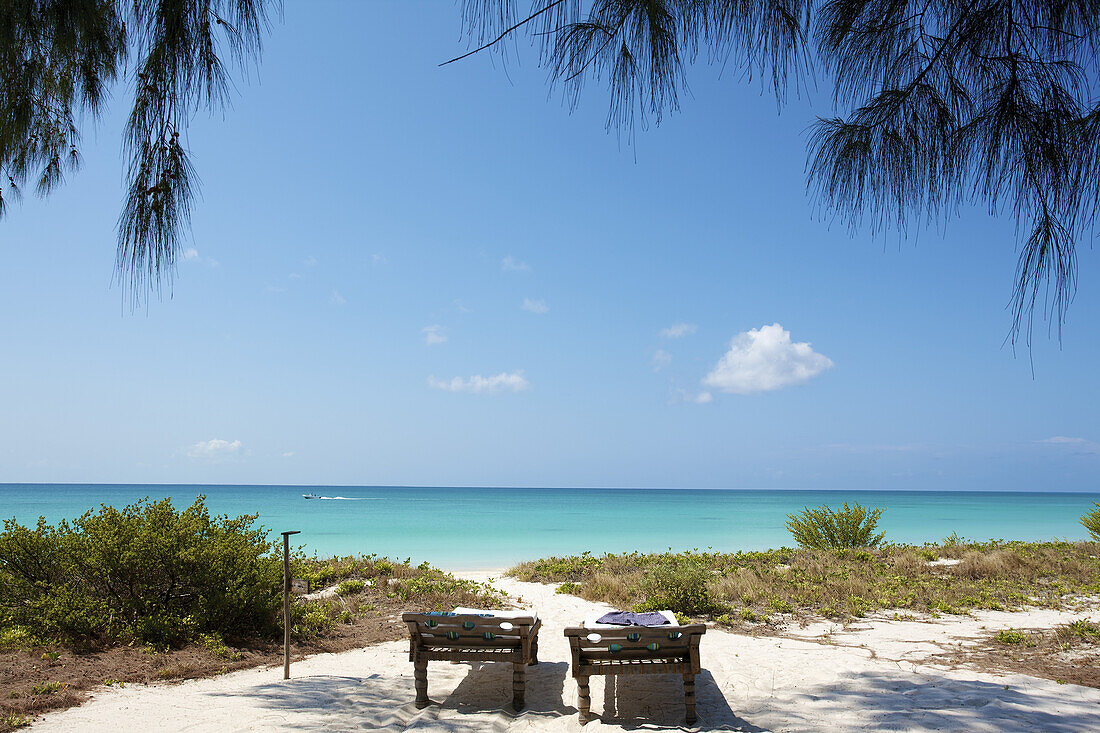 Two Beds Sit In The Shaded White Sand With A View Of The Ocean; Vamizi Island, Mozambique