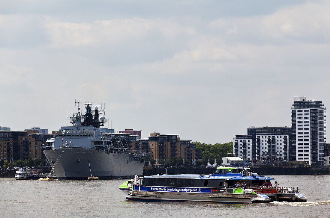 Blick auf die Themse, ein Pendlerboot von Transport For London und die in Greenwich angedockte Hms Ocean; London, England.