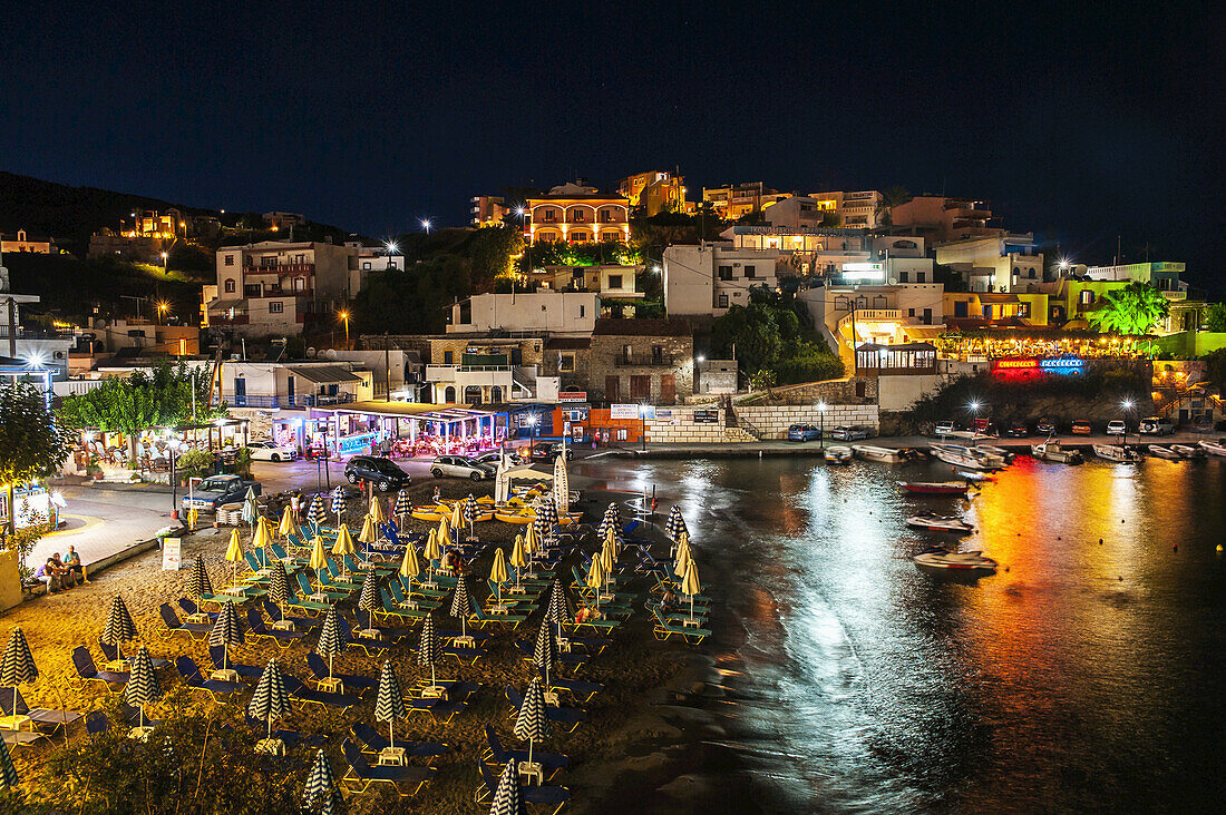 Bunte Lichter leuchten und spiegeln sich im Wasser des Hafens; Bali, Kreta, Griechenland