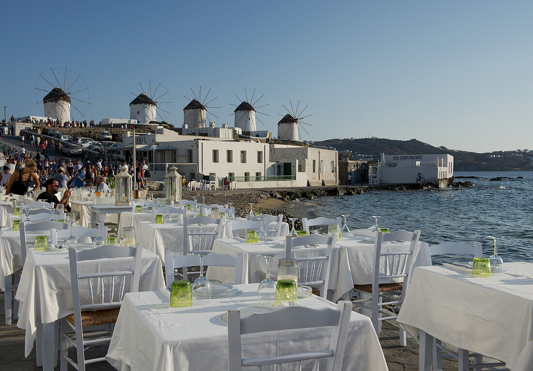 Taverna-Tische für das Abendessen entlang der Strandpromenade in der Gegend von Klein-Venedig; Mykonos-Stadt, Mykonos, Kykladen, Griechische Inseln, Griechenland