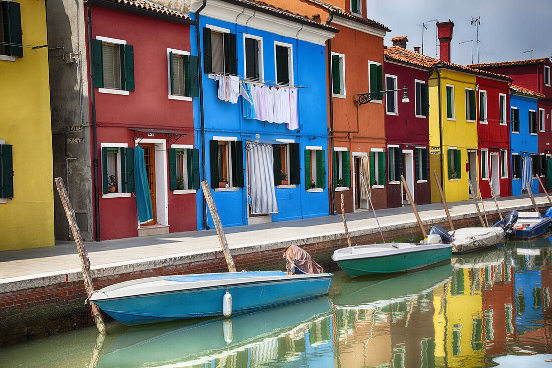 Eine Reihe von bunten Häusern entlang eines Kanals mit Booten; Burano, Venedig, Italien