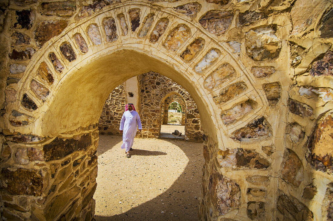 Maure zu Fuß unter dem Bogen eines alten Gebäudes; Taif, Saudi-Arabien