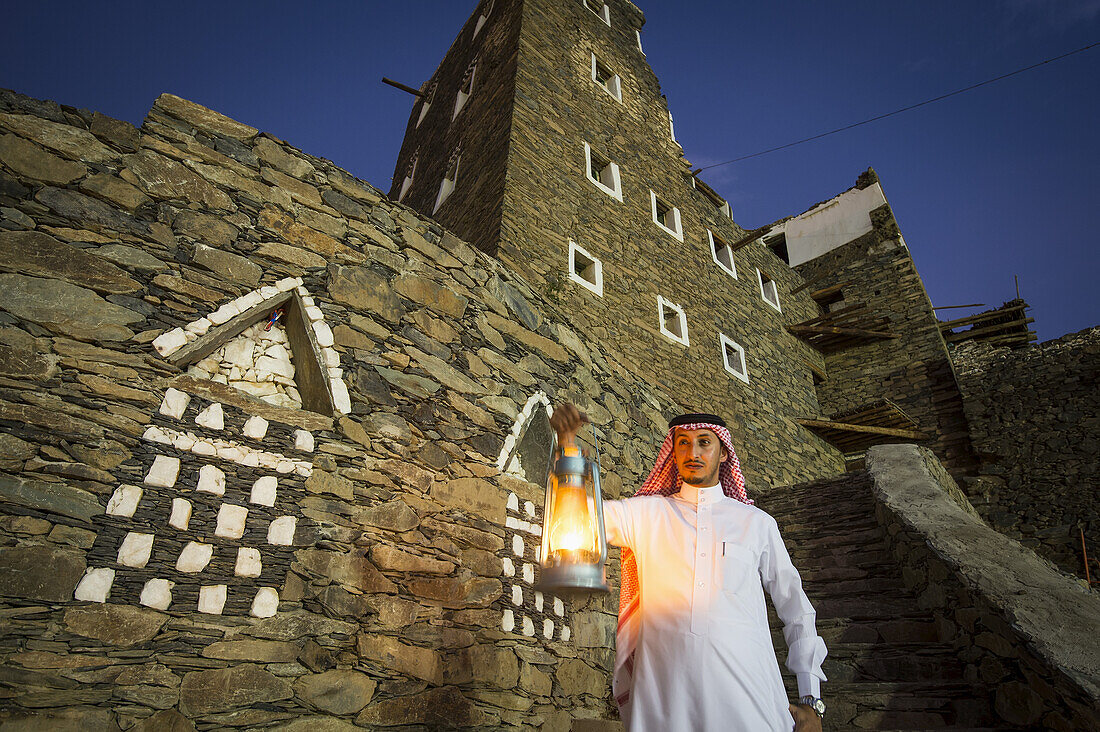 Mann mit Lampe außerhalb des Dorfes Rijal Alma; Provinz Asir, Saudi-Arabien.