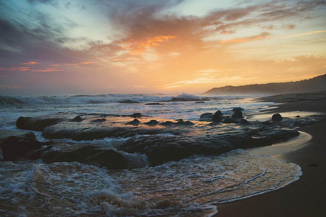 Farbenfroher Sonnenuntergang und angespültes Wasser am Ufer; Tarifa, Cadiz, Andalusien, Spanien