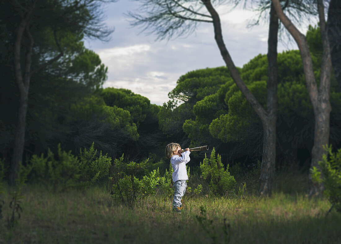 Ein Junge schaut im Gras stehend durch ein Teleskop; Tarifa, Cadiz, Andalusien, Spanien