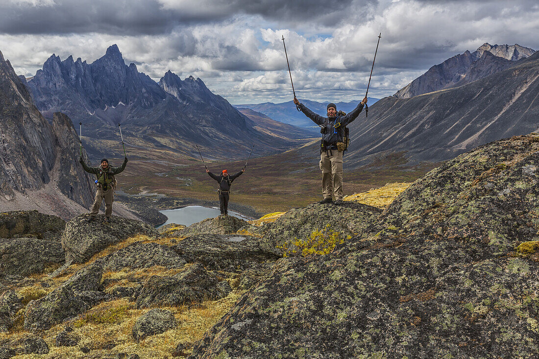 A Group Of Hikers Standing On Rocks Overlooking The Colourful Valleys In Tombstone Territorial Park In Autumn; Yukon, Canada