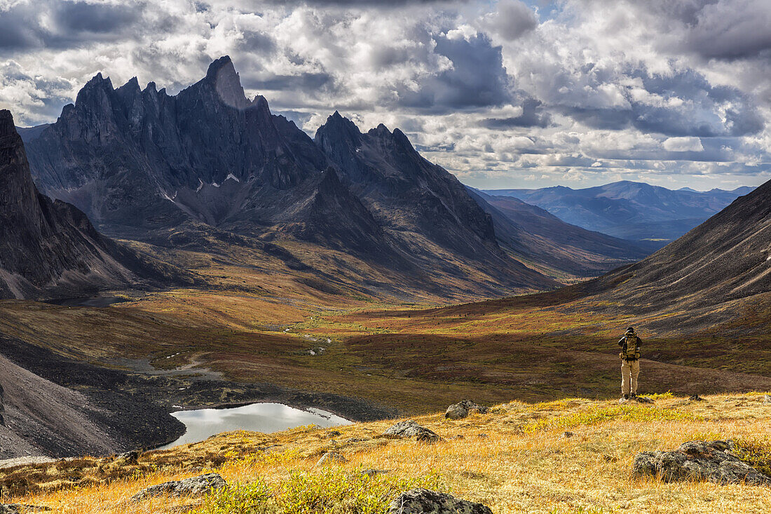 Wanderer steht auf einem Aussichtspunkt und fotografiert die bunten Täler im Tombstone Territorial Park im Herbst; Yukon, Kanada