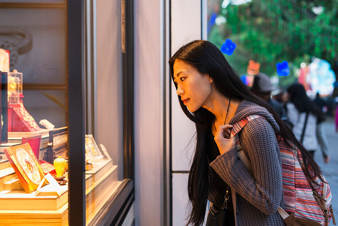 A Young Woman Window Shopping At The Retail Shops Along The Street, Kowloon; Hong Kong, China