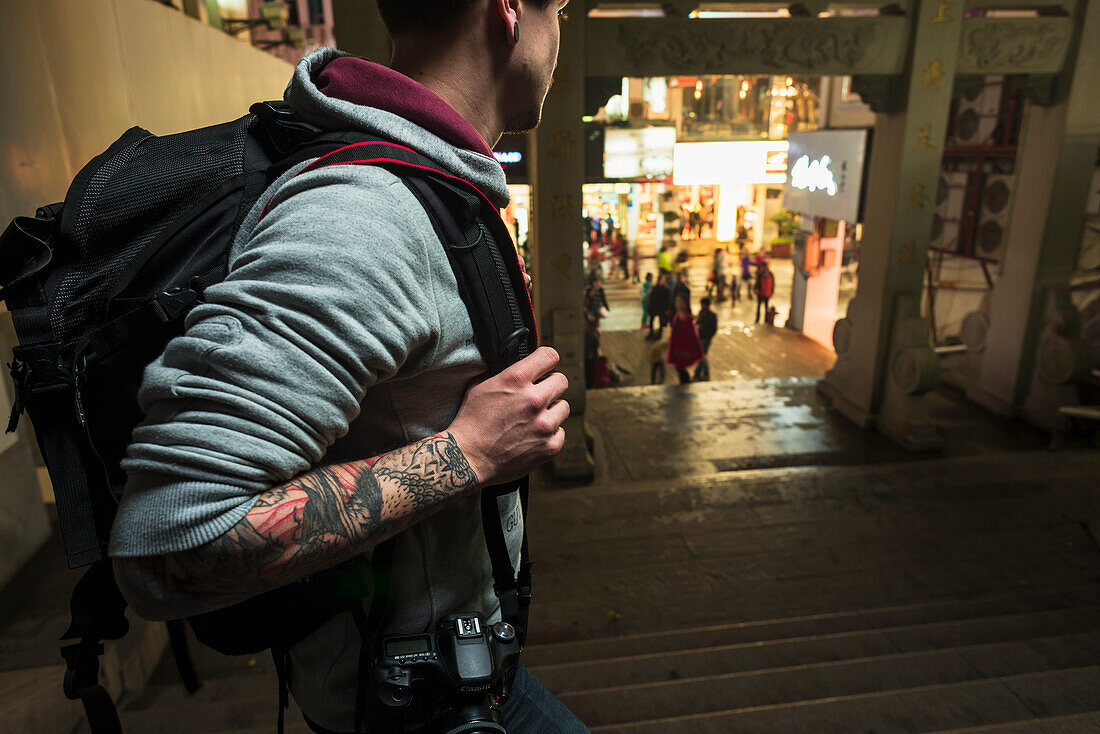 A Male Traveler Looking Towards Retail Shops From The Street; Xiamen, Fujian, China