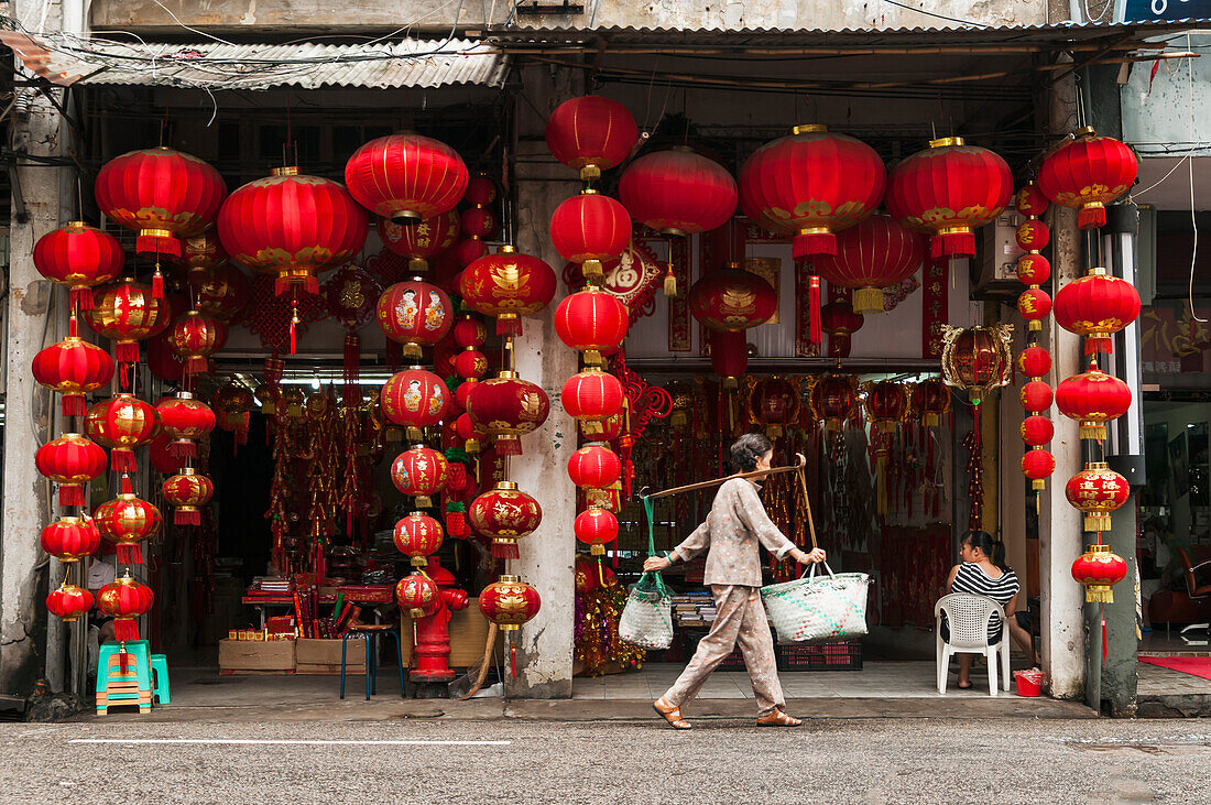 Ein chinesisches Laternengeschäft, eine Frau trägt zwei Taschen mit dem traditionellen Bambus auf der Schulter; Xiamen, Provinz Fujian, China