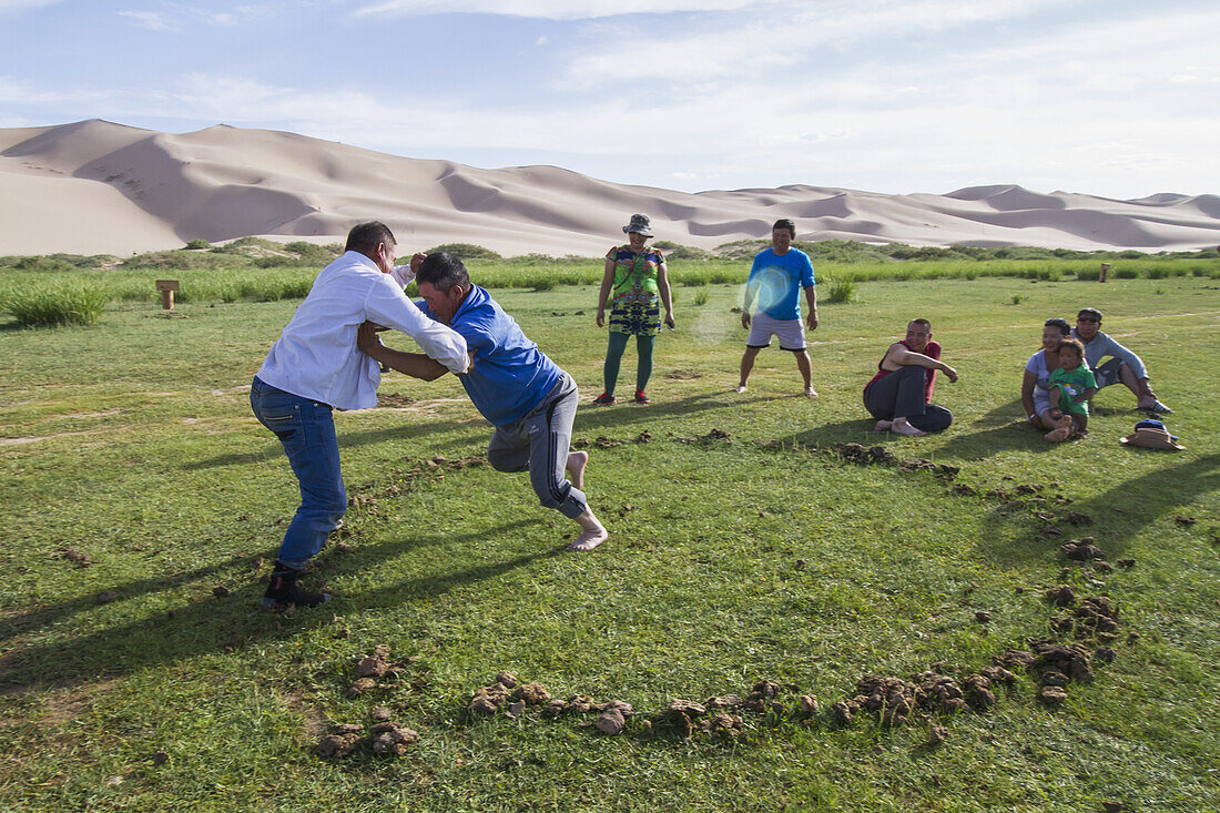 Mongolische Männer ringen in der Oase Seruun Bulag bei den Sanddünen von Khongoryn Els, Gobi-Gurvansaikhan-Nationalpark, vEmnv?govi-Provinz, Mongolei