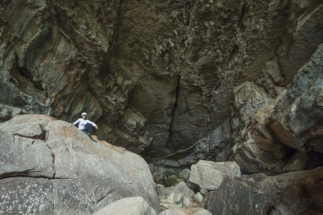 Eine Frau sitzt am Eingang einer großen Höhle im Toro-Toro-Nationalpark; Bolivien