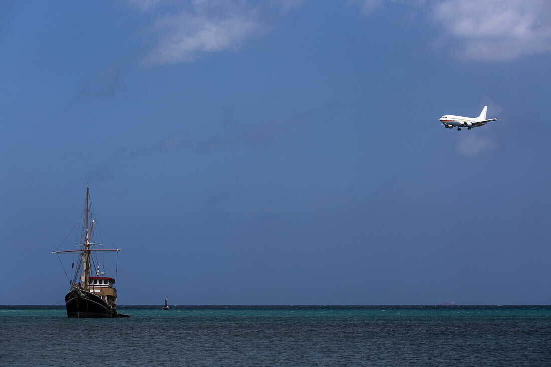 Commercial Passenger Airplane On Approach To Aruba's International Airport, Flying Over Blue Sea And Fishing Trawler, Surfside Beach; Aruba