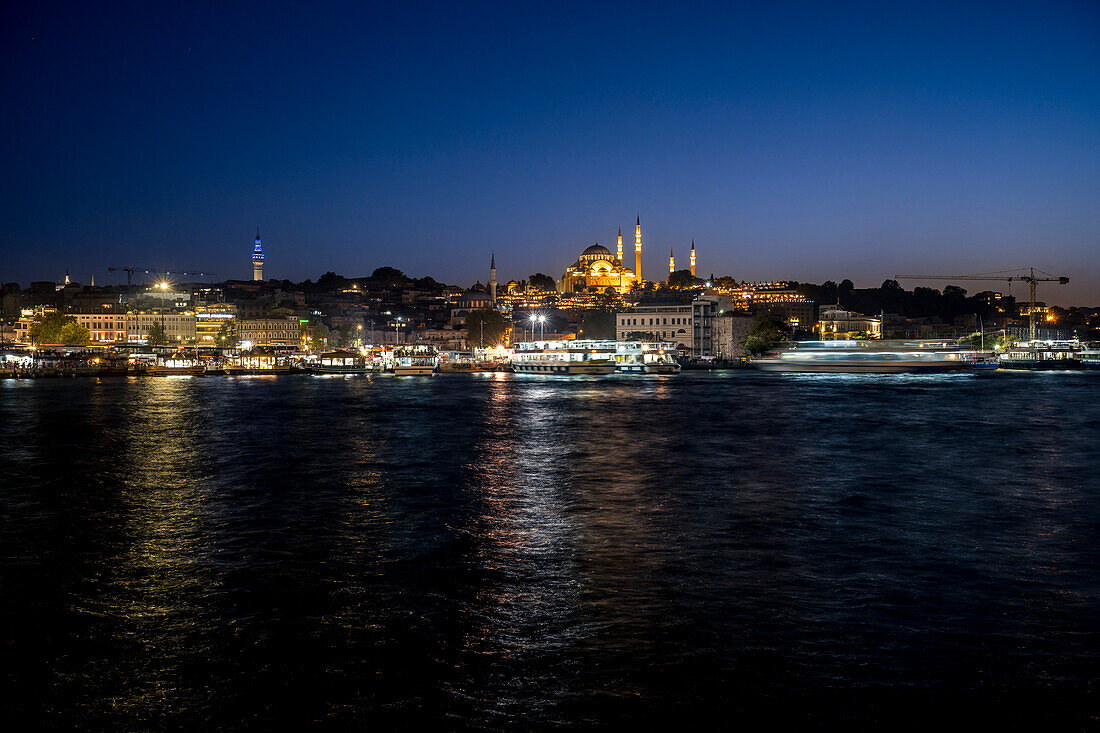 Distant Suleymaniye Mosque and Istanbul waterfront illuminated at night; Istanbul, Turkey