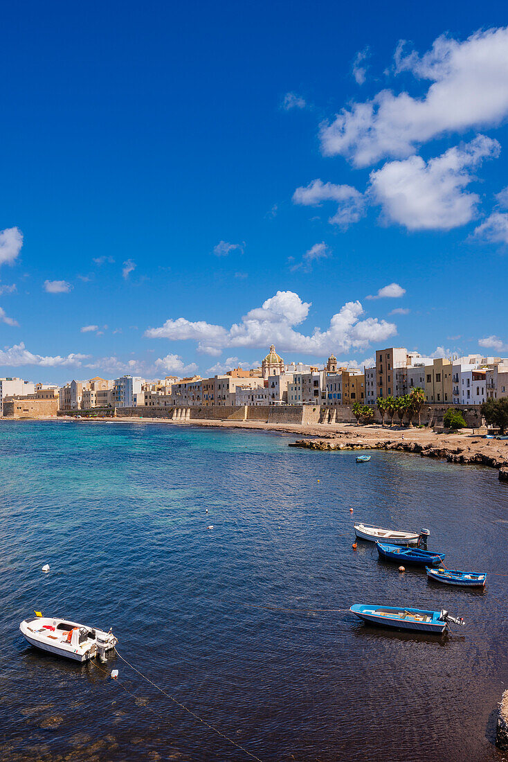 Kleine Boote am Ufer der Skyline von Trapani mit alten, steinernen Gebäuden und der Ufermauer; Trapani, Sizilien, Italien