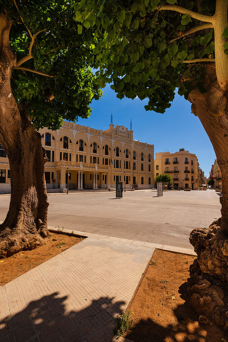 Blick durch Bäume auf das Postgebäude in Trapani Stadt; Trapani, Sizilien, Italien.