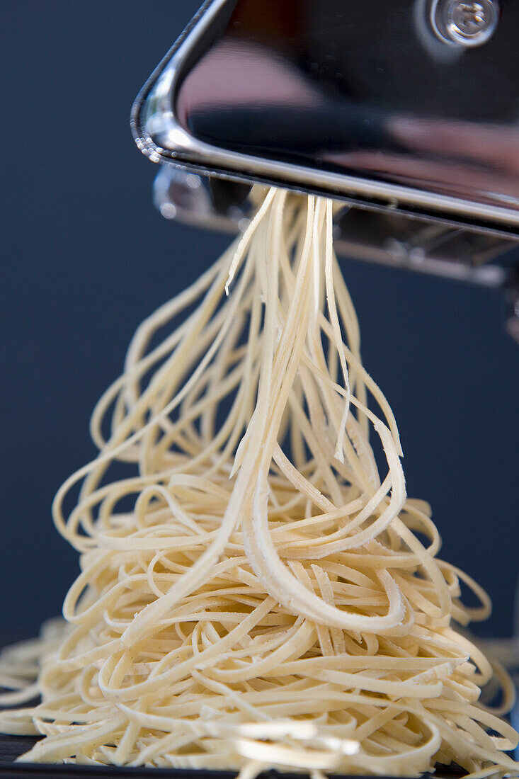 Heap of fresh tagliolini coming out of a pasta maker