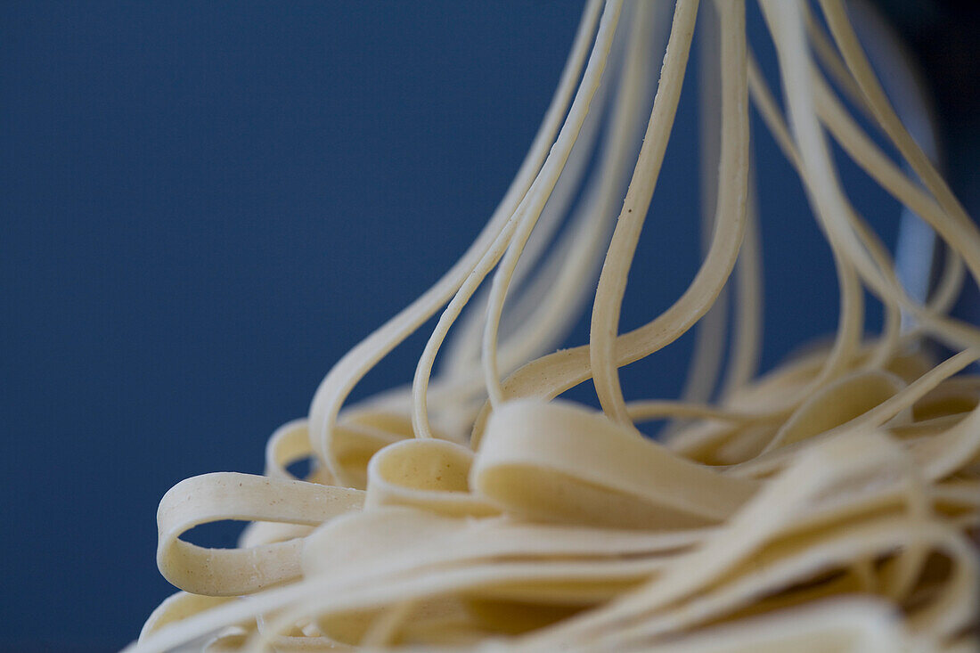 Haufen frischer Tagliatelle, die aus einer Nudelmaschine kommen