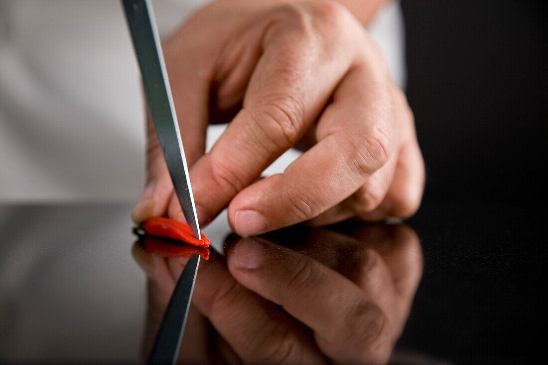Close up of a chef hands deseeding a red bird's eye chili