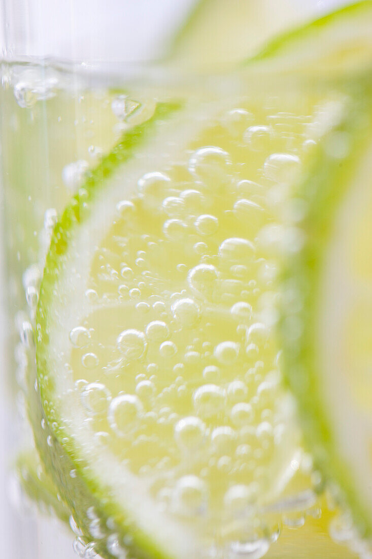 Extreme close up of slices of lime floating in sparkling water