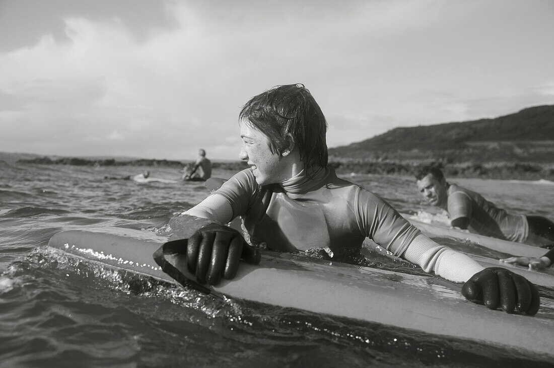 Teenaged boy in the sea holding on to his surfboard