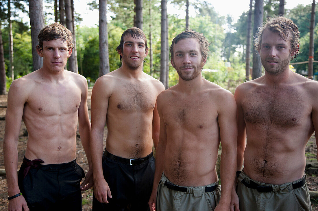 Junge Männer stehen ohne Hemd und nass in einem Wald